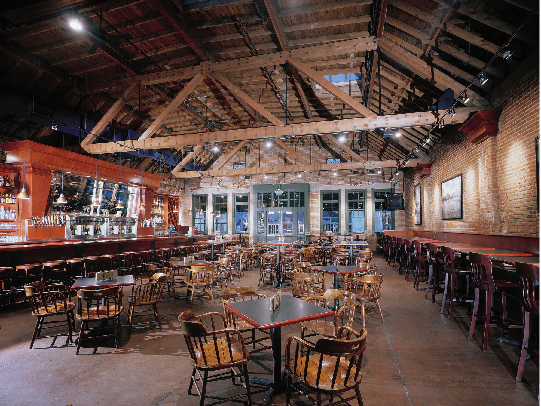 Interior of Bardenay restaurant in Boise — exposed timber trusses, brick walls, long bar, concrete floors