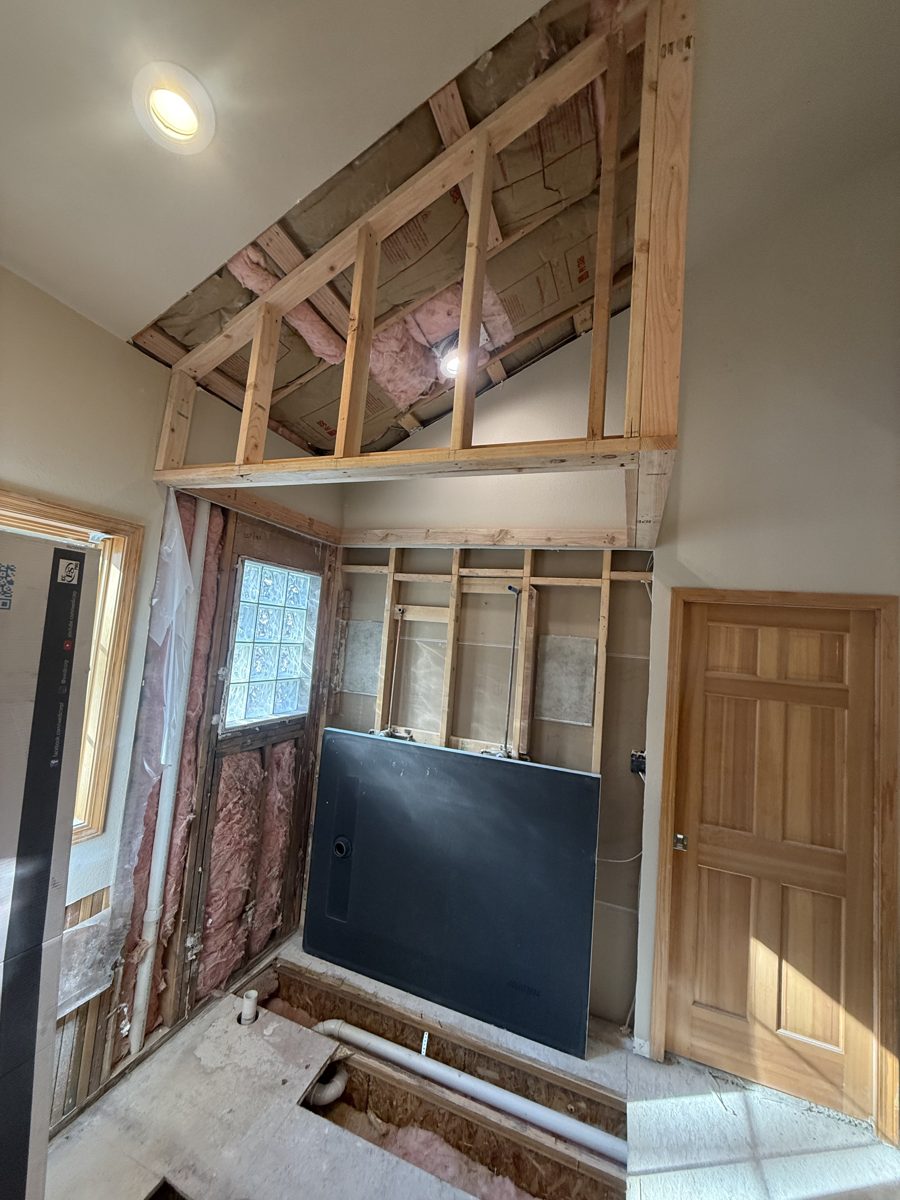 New wall framing and the first sheets of tile backer board installed in a bathroom remodel
