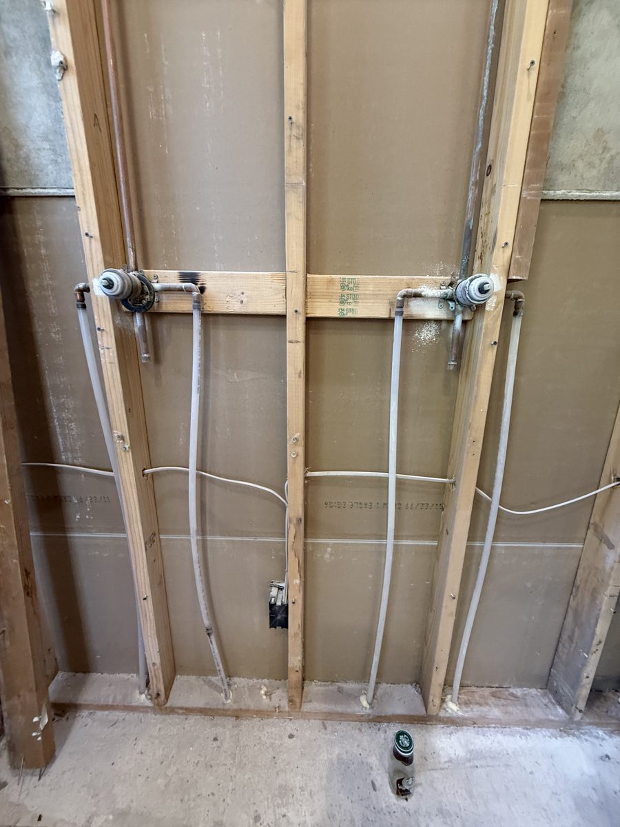 New shower valves and supply lines roughed in on new wood blocking in an open bathroom wall