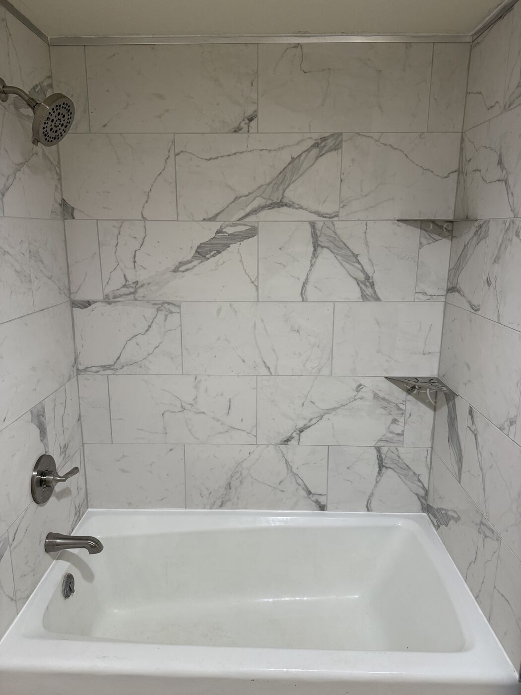 Finished white tile tub surround in a bathroom remodel