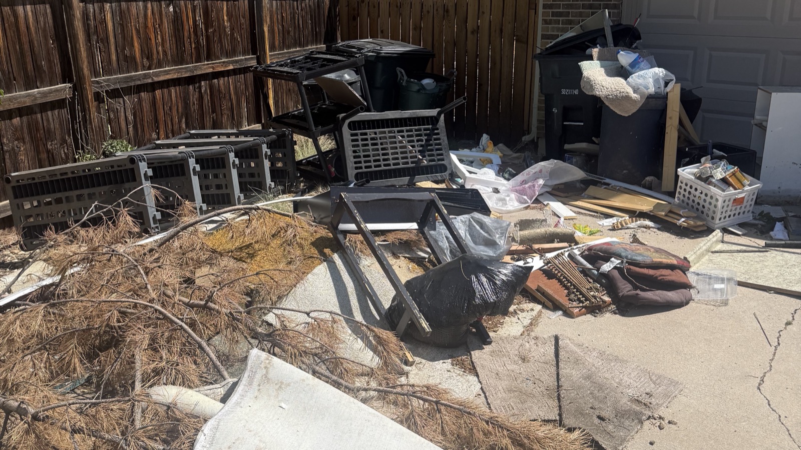 Pile of abandoned furniture, plastic crates, rugs, and yard debris left in a Colorado Springs driveway after a tenant eviction
