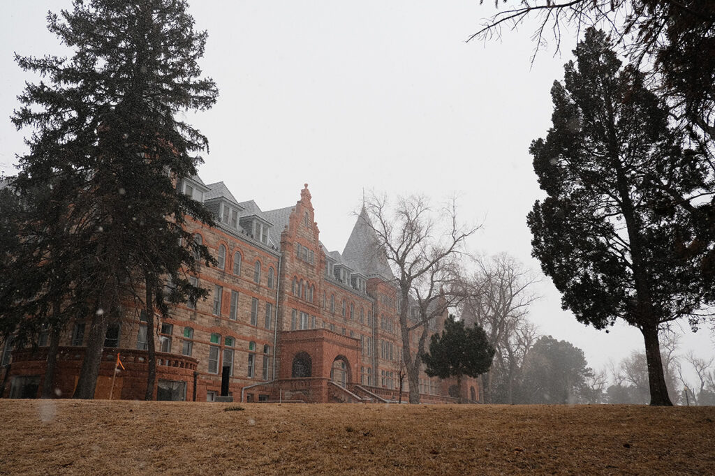 The Union Printers Home main building in winter, framed by large evergreen trees